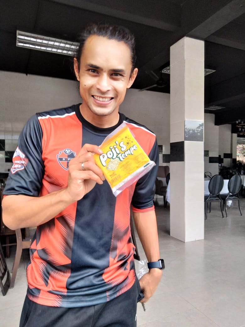 Seorang pelanggan tersenyum sambil menunjukkan pek Pojie’s Tempe